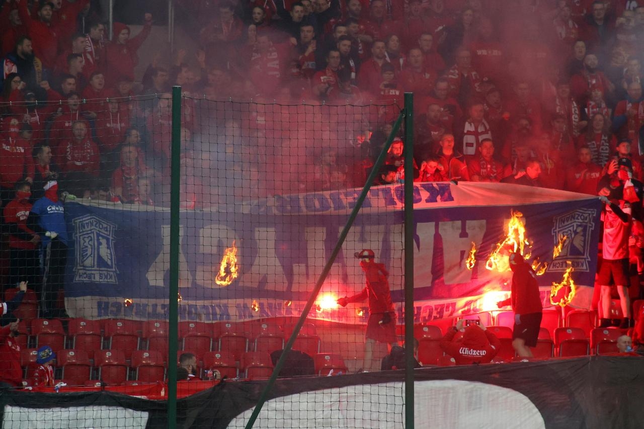 Kibice Widzewa Łódź palą baner Lecha Poznań podczas meczu | fot. PAP/Marian Zubrzycki